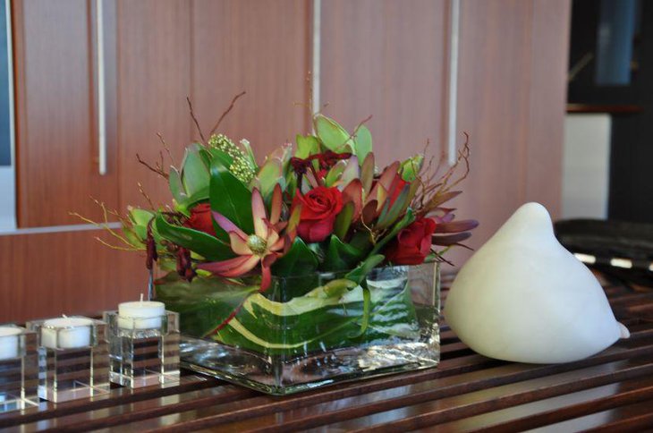 Flower blooms and green leaves in square glass vase for St Patricks Day table centerpiece