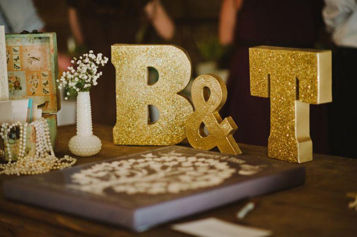 Golden glitter monogram decor on wedding sweetheart table