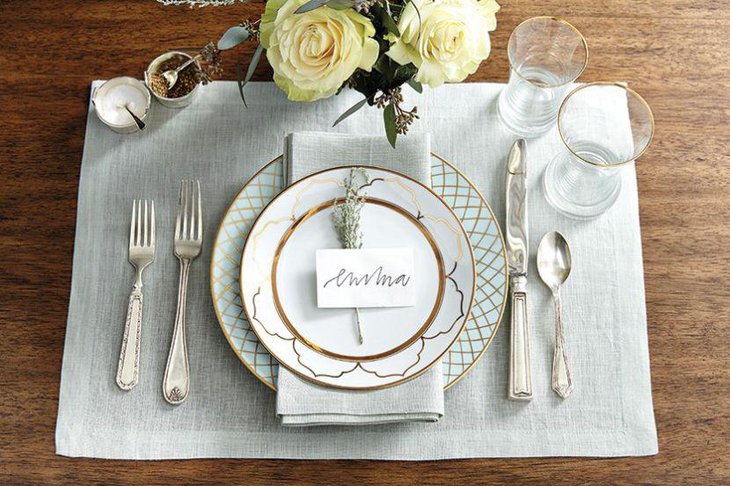 Holiday dinner table decor with golden rimmed plates and flowers