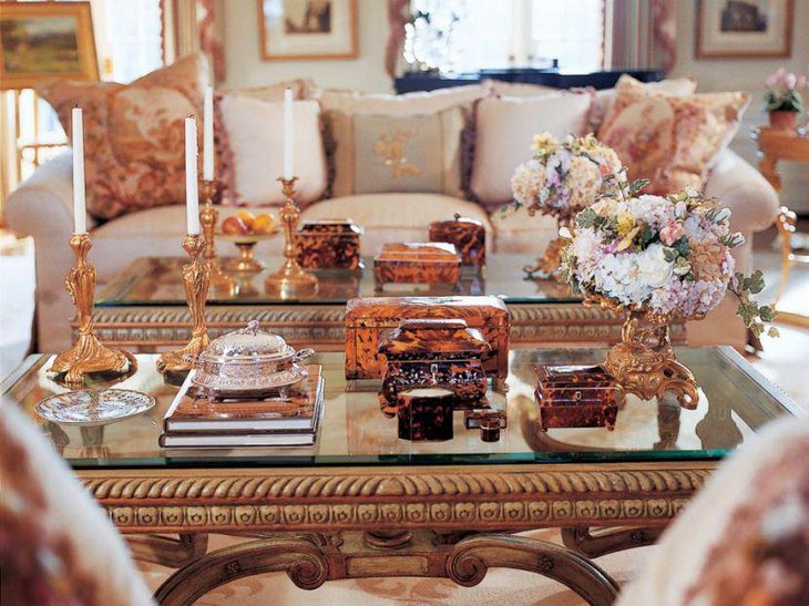 Ornately carved candleholders and flower bouquet as coffee table centerpiece