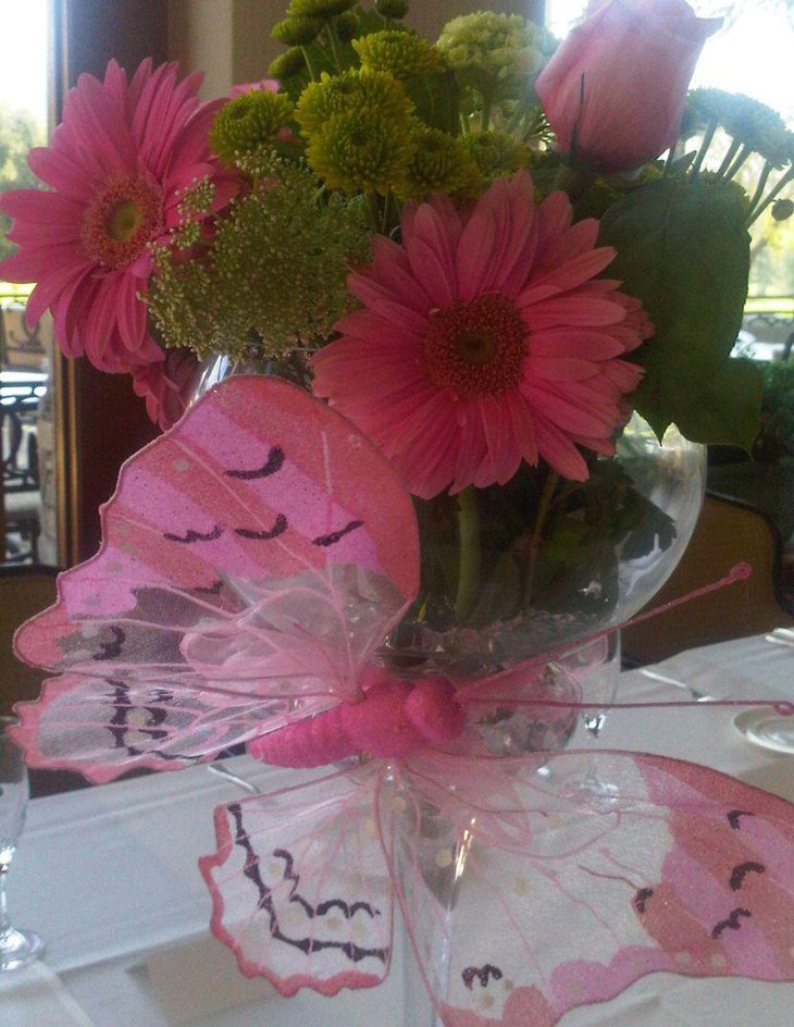 Pink butterfly and floral centerpiece decoration on girl baby shower table