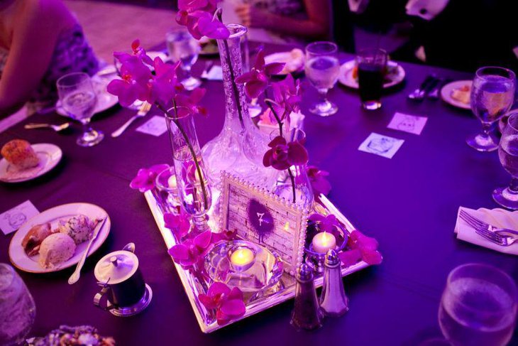 Purple themed party table setting with tall glass vase and lavender flower