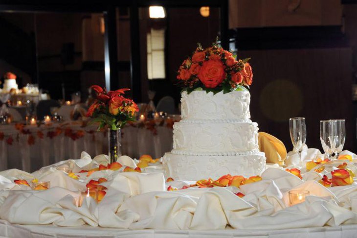 Red floral decor on wedding cake table