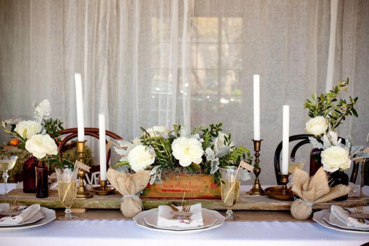 Rustic themed country wedding table decked up with wooden vase and burlap wrapped decorations