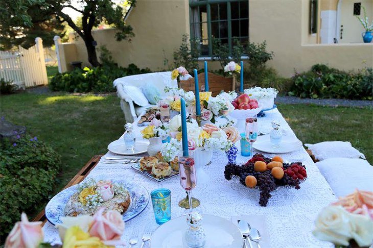 Stylish garden party table decor with blue candles and yellow roses