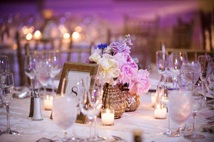 Stylish gold vase and flowers as wedding centerpiece on table