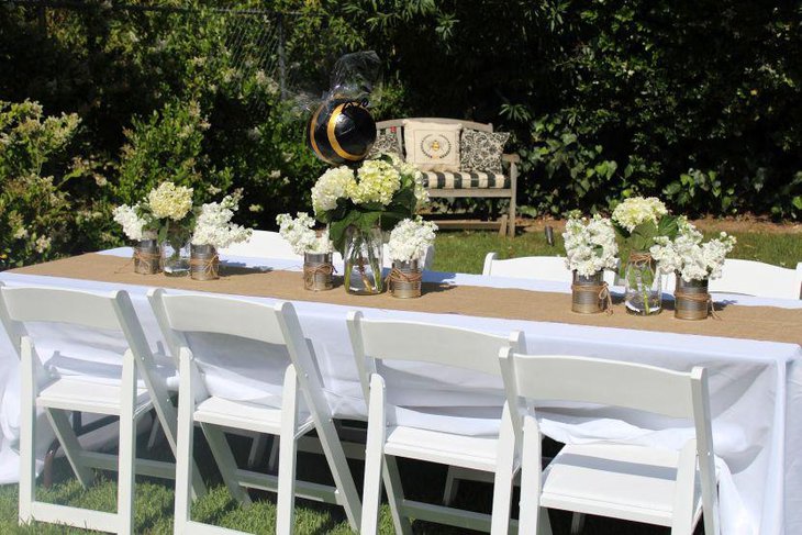 Vintage party table decor with paper mache bees tin cans and jar floral centerpieces