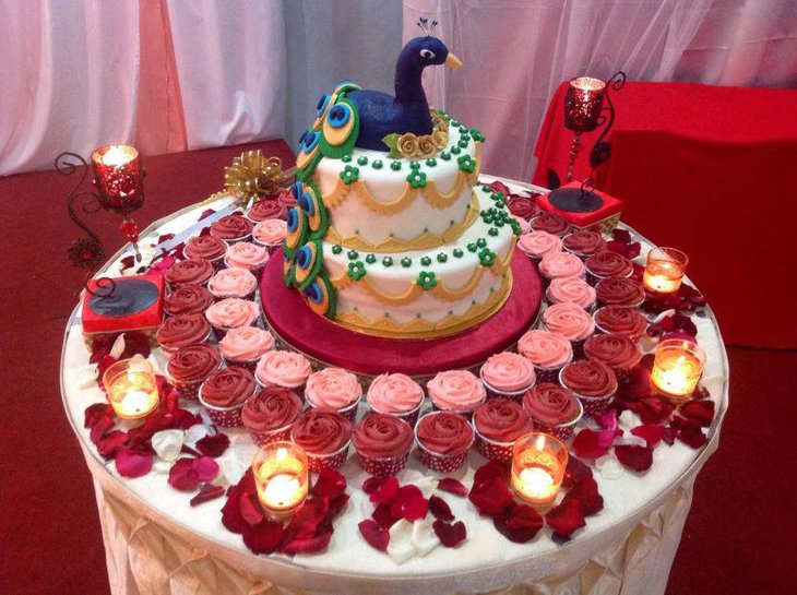 Wedding peacock cake table decor with rose petals and votive