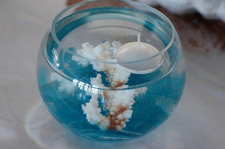 Wedding table centerpiece with glass bowl filled with coral and candle