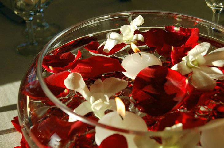 Wedding table decor with round glass bowl filled with floating candles and petals