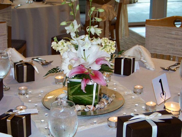 Wedding table setting with white floral centerpiece and golden ribbon wrapped black gifts